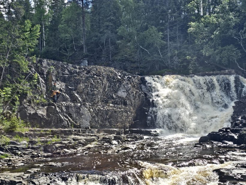 Fossefall med en speider som klatrer opp ved siden av den