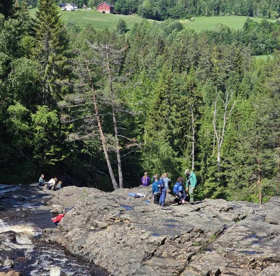 Speidere står ovenfor en foss og leter etter fossiler