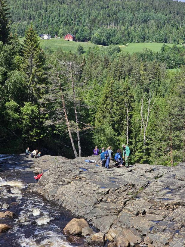 Speidere står ovenfor en foss og leter etter fossiler